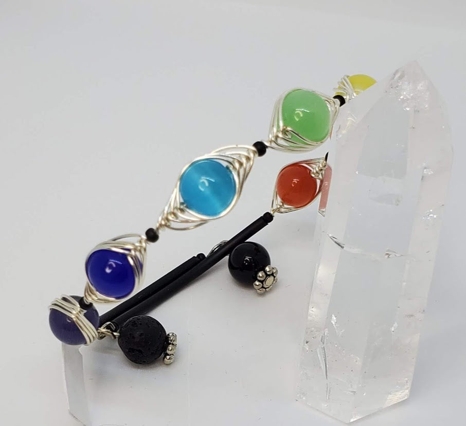 Herringbone wrapped Cat's Eye glass beads in Chakra color order with a lava bead for essential oil diffuser.  One size fits most.