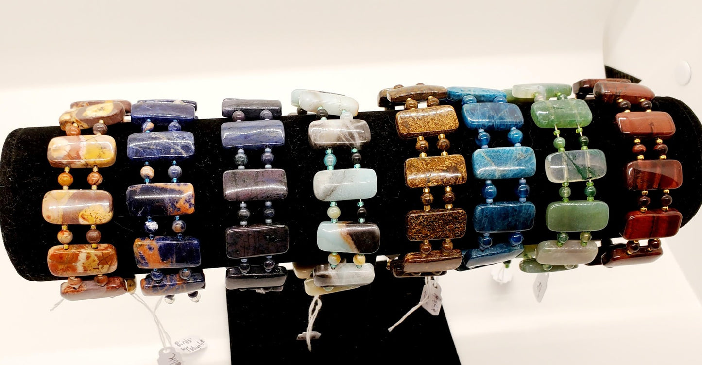 From left to right: Bird's Eye Rhyolite, Orange & Blue Sodalite, Dumortierite, Black & Gold Amazonite, Bronzite, Apatite, Moss Agate, Red Tiger Eye