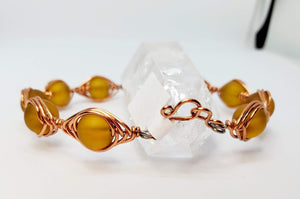 Amber colored Sea Glass wrapped in a herringbone copper wire with handmade hook clasp.