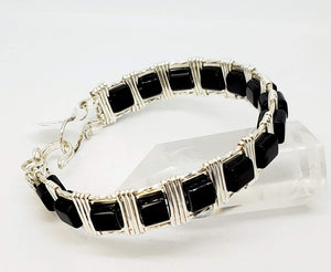 Glossy black glass cubes with anti-tarnish finish on silver plated copper wire. Handcrafted clasp that adds to the attractiveness of this comfortable oval shaped bracelet. The twisted wire edges add a touch of Bling.